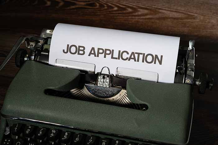 Frase "Job application" escrita sobre un folio en blanco colocado en una máquina de escribir antigua.
